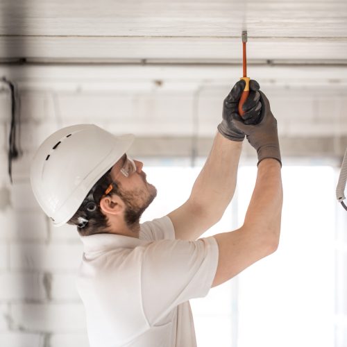 Electrician installer with a tool in his hands, working with cable on the construction site. Repair and handyman concept. House and house reconstruction.